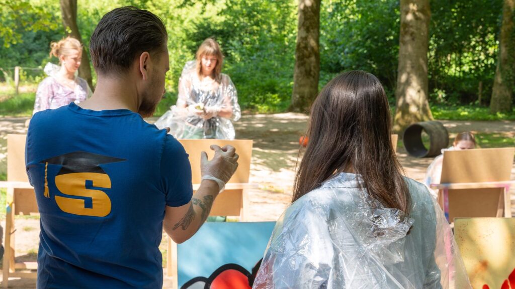 Begeleider helpt een deelnemer tijdens de Workshop Graffiti.