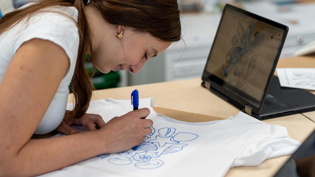 Leerling gebruikt voorbeeld om na te tekenen tijdens de Workshop T-Shirt Ontwerpen.