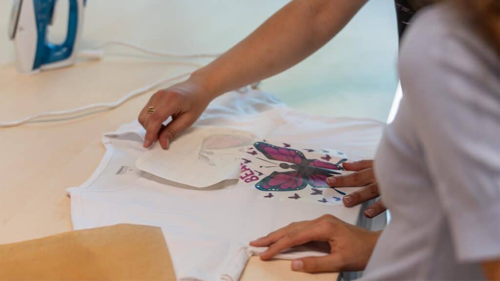 Workshopdocent helpt leerling met het losmaken van het sjabloon tijdens de Workshop T-Shirt Ontwerpen.