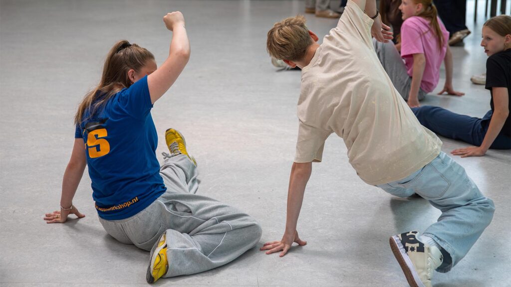 Workshopdocent en begeleider doen een oefening van de Workshop Breakdance.