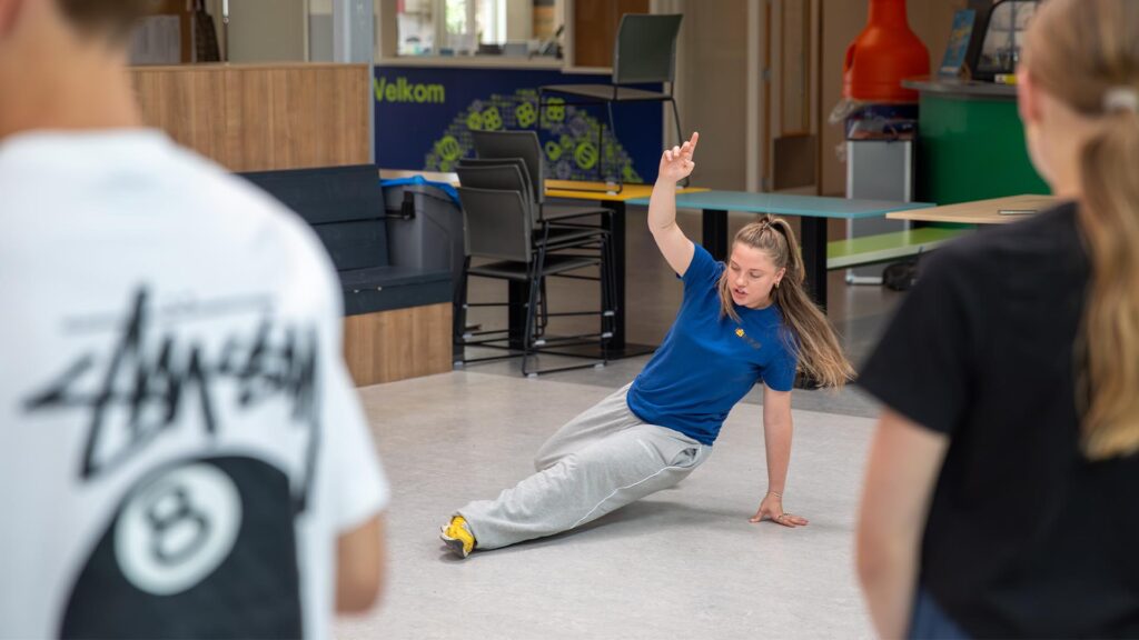 Workshopdocent doet een oefening voor van de Workshop Breakdance.