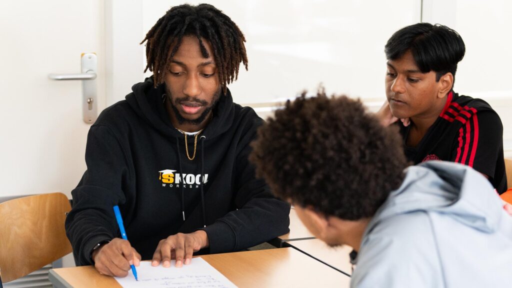 Deelnemers schrijven de tekst voor de rap onder begeleiding van de workshopdocent tijdens de Workshop Rap. en de Nationale Onderwijsweek