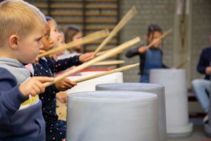 Groep leerlingen maakt samen ritme tijdens een muziekworkshop op school.