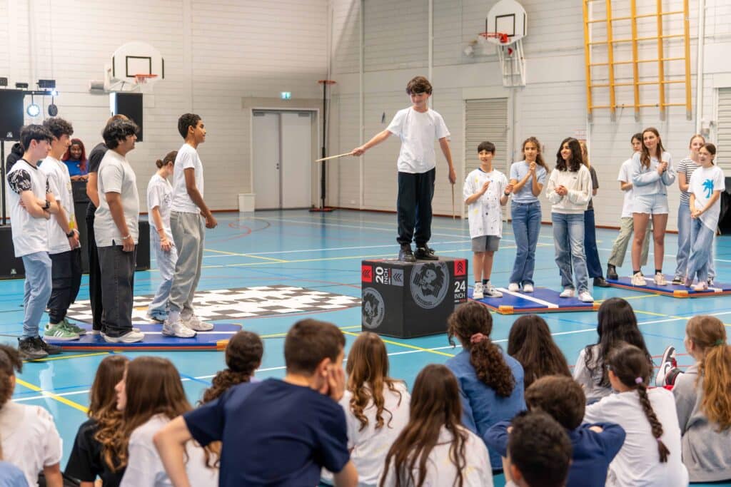 Leerlingen doen samen een dansbeweging buiten op het schoolplein