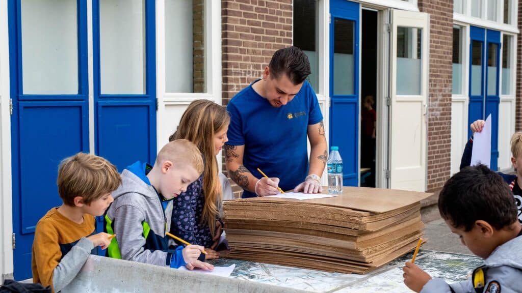 Kinderen van de BSO krijgen hulp van de workshopdocent met de activiteit in de herfstvakantie.
