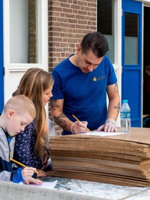 Kinderen van de BSO krijgen hulp van de workshopdocent met de activiteit in de herfstvakantie.