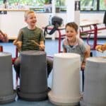 Kinderen van de BSO lachen tijdens de Workshop Ghetto Drums die wordt verzorgd door Skool Workshop als activiteit in de herfstvakantie.