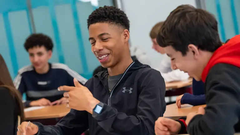 Leerlingen werken lachend samen aan tafel tijdens een CKV-dag