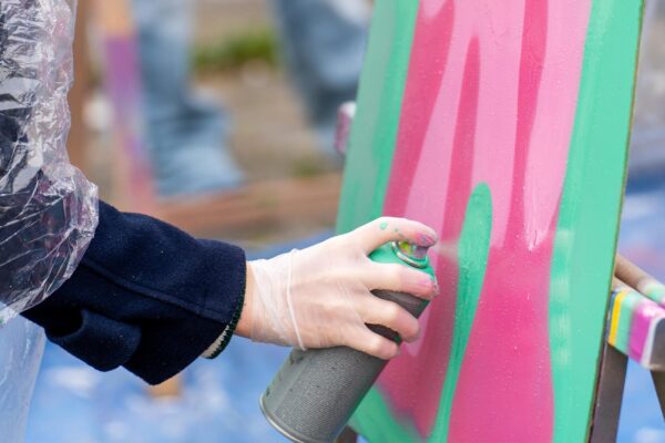 Deelnemer spuit graffiti op houten plaat tijdens Workshop Graffiti en tijdens het Graffiti Vrijgezellenfeest