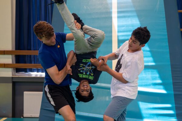 Deelnemer doet een salto onder begeleiding bij de Workshop Freerunning.